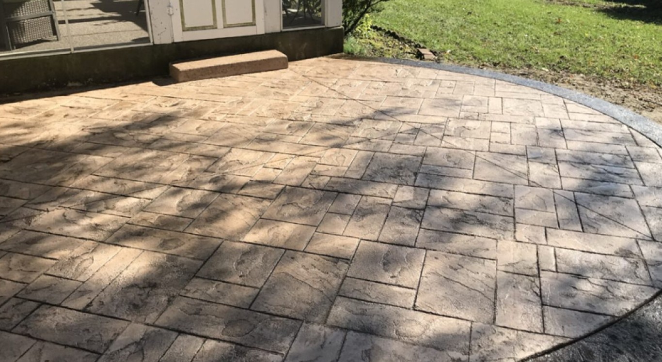 Decorative stamped concrete patio with stone tile pattern and curved edges